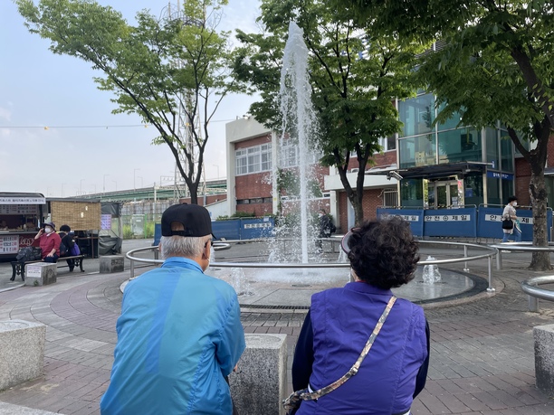 an old couple watching a fountain